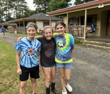 Group of campers smiling outside in the woods at overnight summer camp.